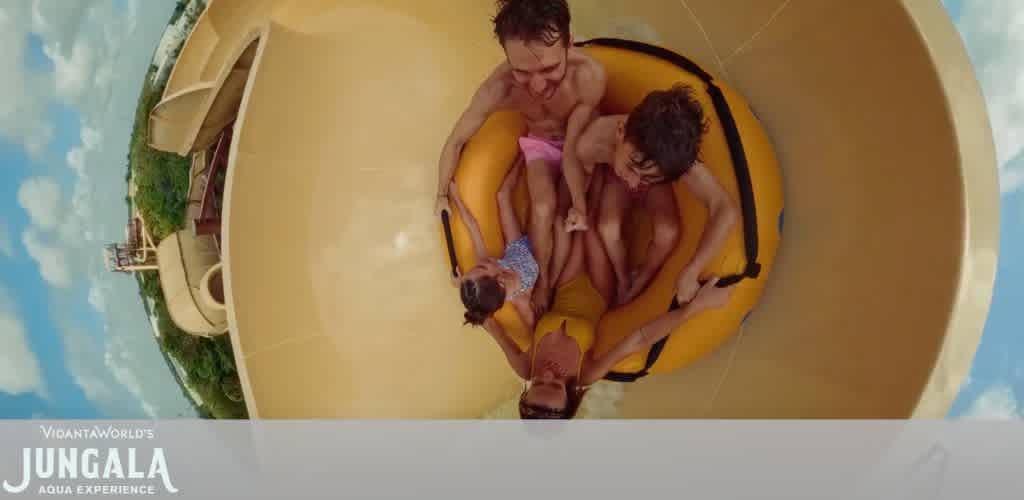 Two adults and two children enjoying a water slide at Ungala Aqua Experience on a sunny day.