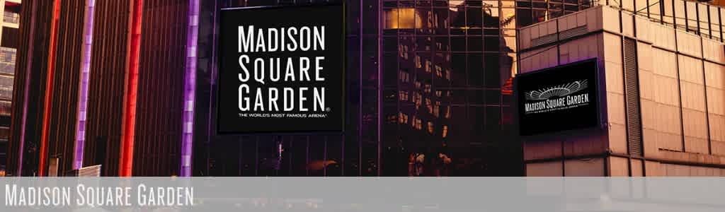 A large digital billboard displays Madison Square Garden with surrounding modern glass buildings at dusk