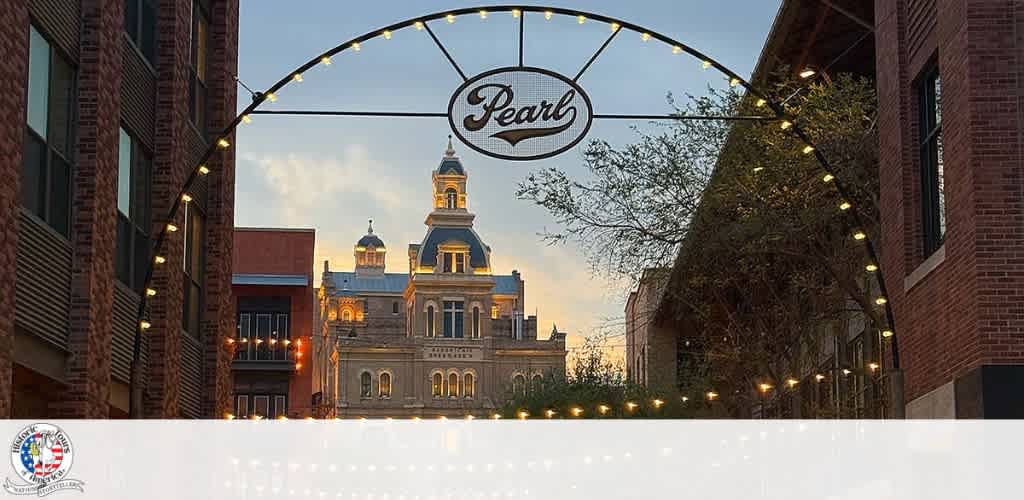 Archway over a street with string lights and a historic building in the background