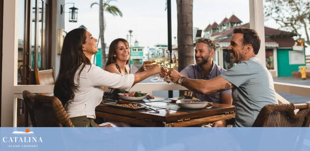 Four people seated outdoors at a restaurant, toasting with wine glasses.