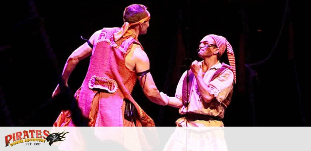 Two performers in pirate costumes on stage, engaged in interaction, with a 