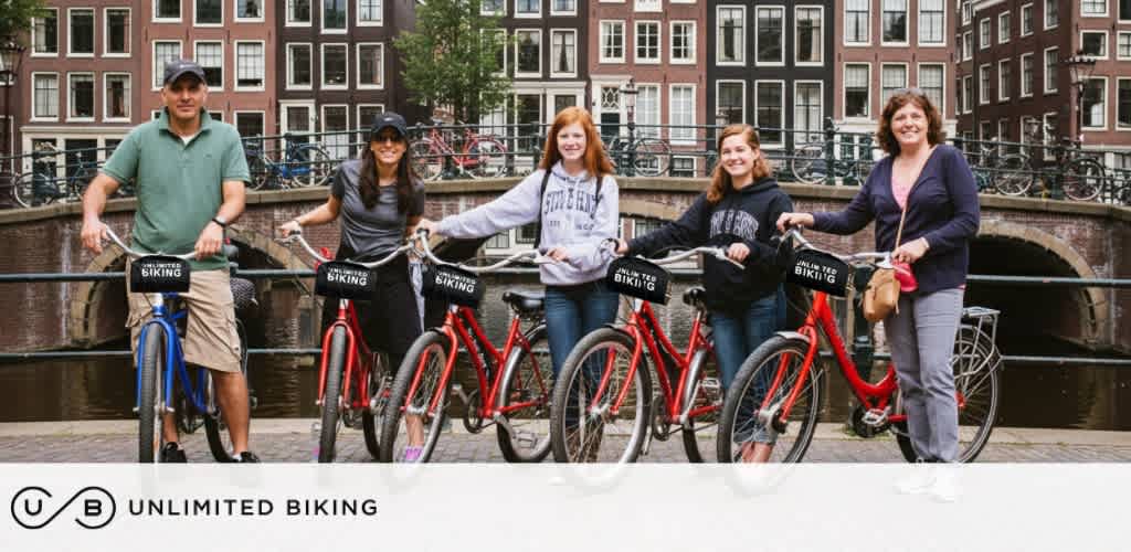 Group of five people with bikes standing by a canal with brick buildings in the background during daytime
