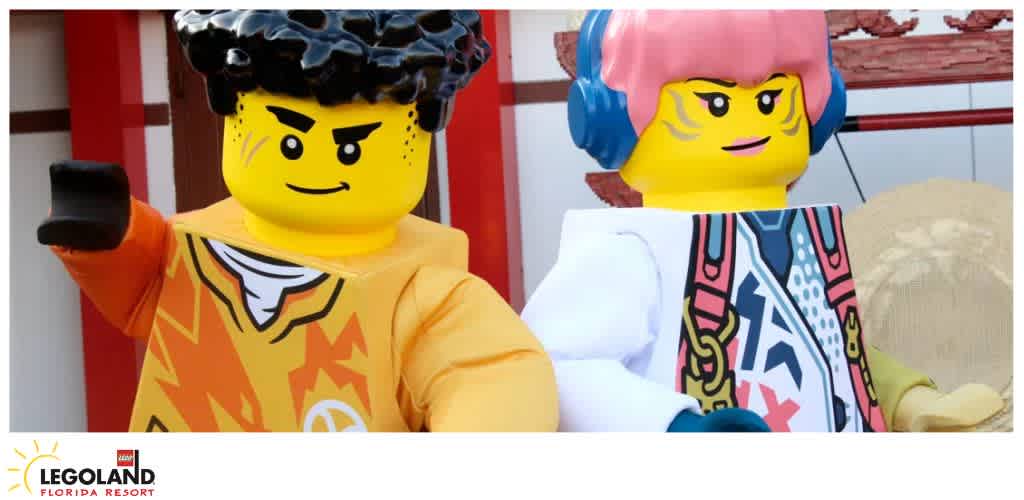 Two life-sized LEGO characters with vibrant outfits and colorful background.