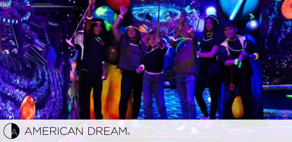 A group of people at a glow-in-the-dark space-themed mini-golf course with neon accessories.