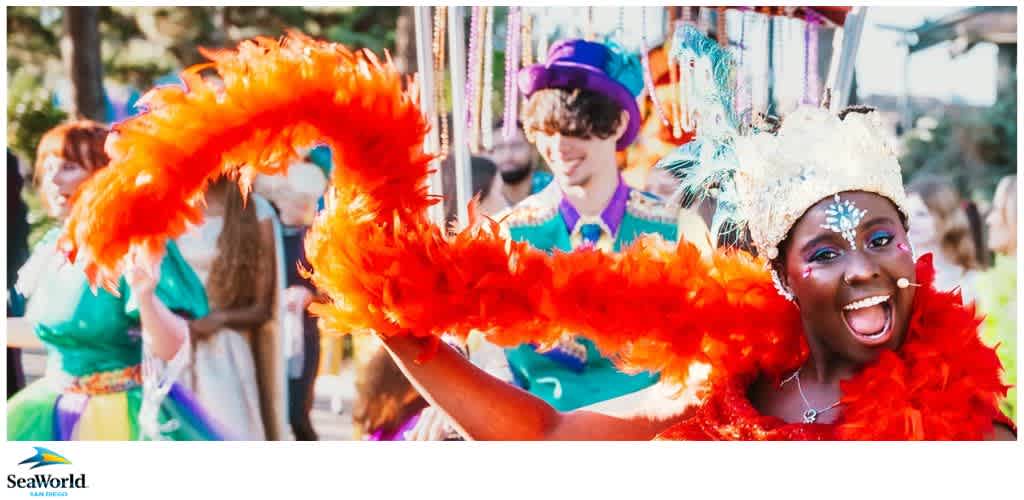 Person in colorful costume with red feather boa at a parade in SeaWorld San Diego