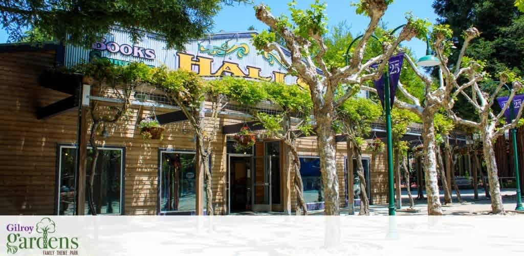Front view of a building with wood paneling and twisty trees in a sunlit setting.