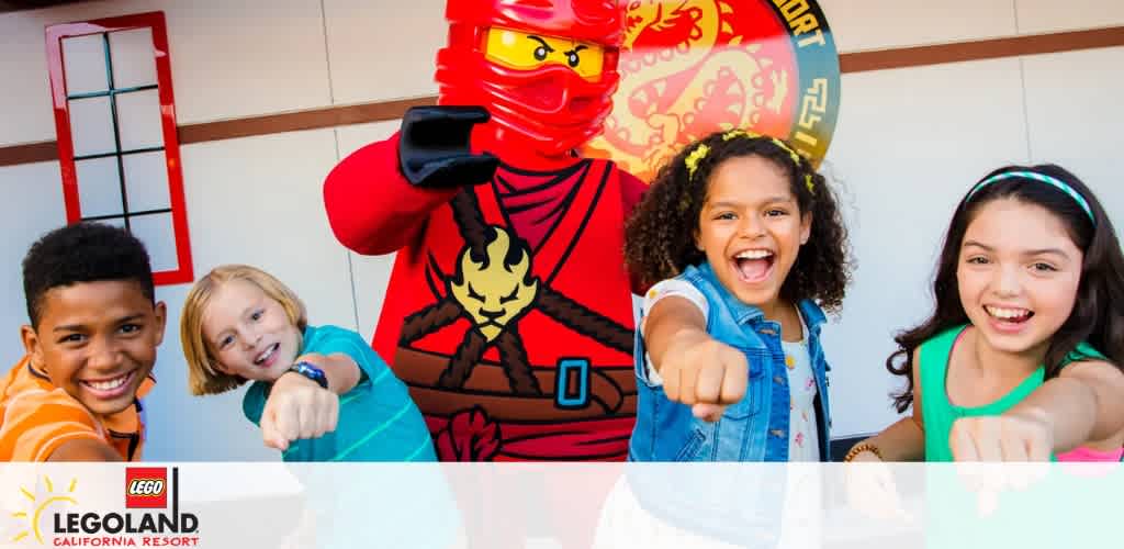 Children posing with a red LEGO ninja figure at LEGOLAND California Resort.