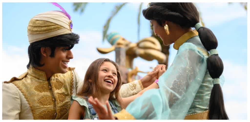 Children and adults in colorful costumes sharing joyful moments outdoors on a sunny day.