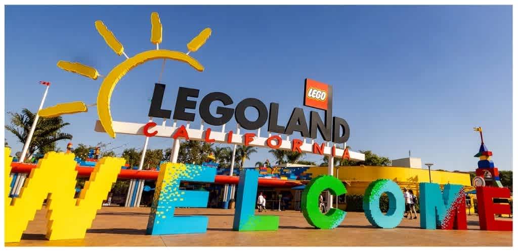 Colorful large letters spelling out Welcome at the entrance of Legoland California with a bright sky and playful structures in the background