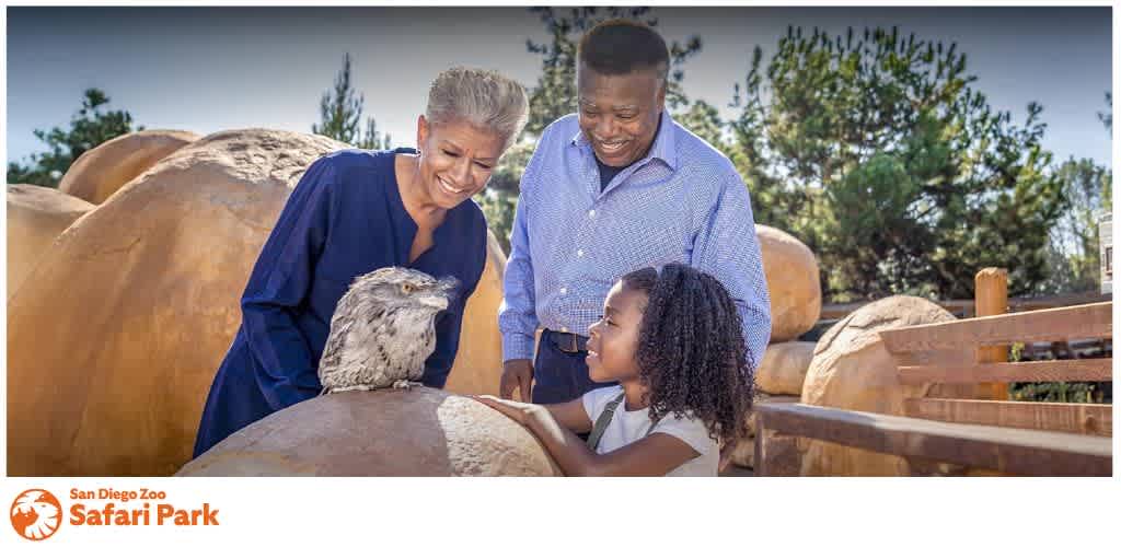 Three people interacting with a bird at the San Diego Zoo Safari Park.
