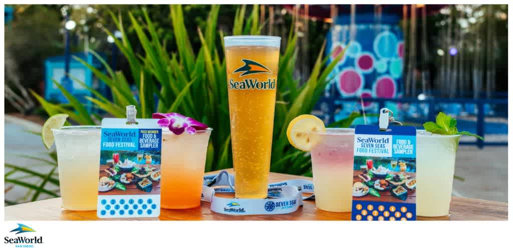 Five beverages on a table with SeaWorld branding and promotional cards for the SeaWorld Seven Seas Food Festival.