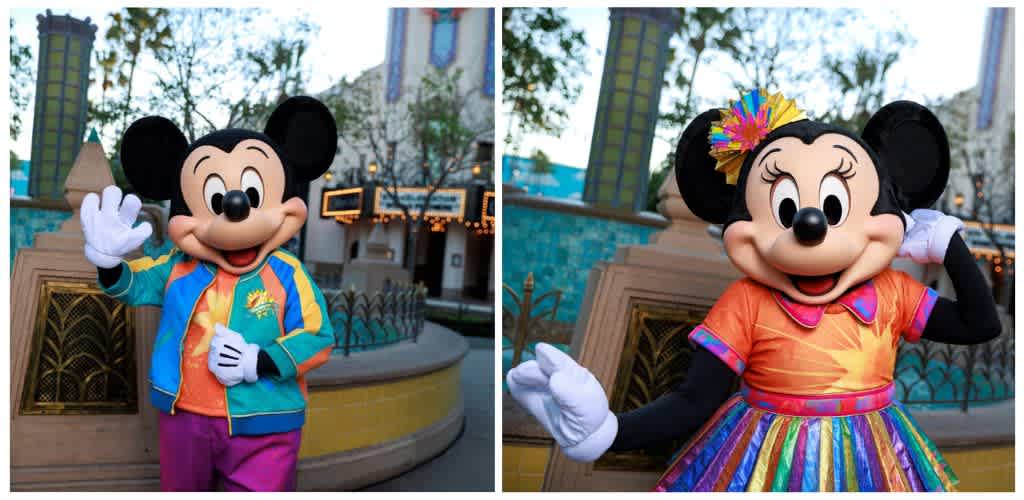 Costumed Mickey Mouse and Minnie Mouse characters standing outdoors with trees and funpark structures in the background.