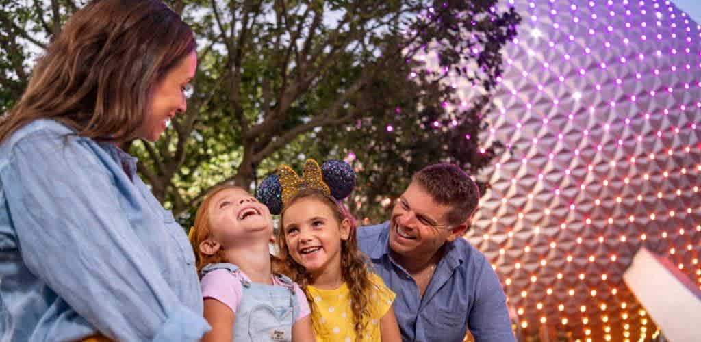 A family enjoying a night outdoors with colorful lights and smiling children and adults, creating a joyful and festive atmosphere.