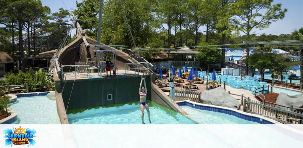 People enjoy water slides waterside pool and lounge chairs at Shipwreck Island Waterpark on a sunny day.