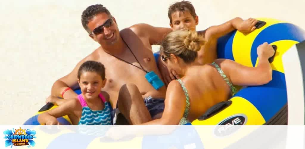A family enjoys riding an inflatable water tube together on a sunny day at Shipwreck Island Waterpark.