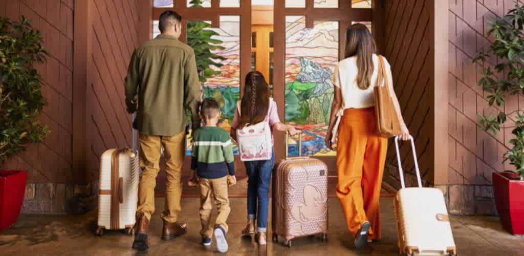A family with luggage entering the Disney Grand Californian Hotel & Spa at Disneyland Resort, ready to begin their Disney adventure.