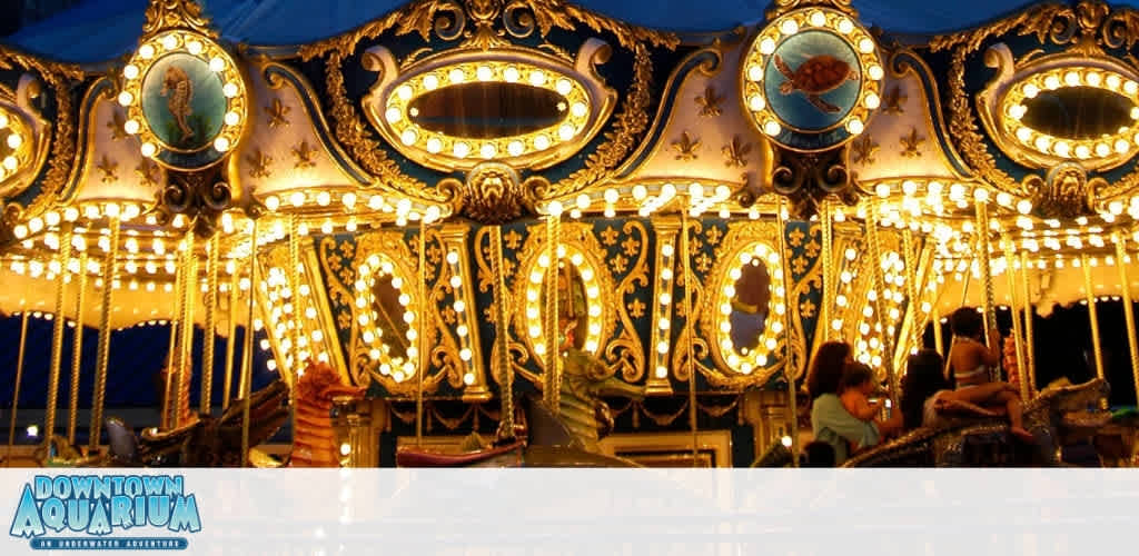 A brightly lit vintage carousel with illuminated signs and children riding carousel animals at sunset