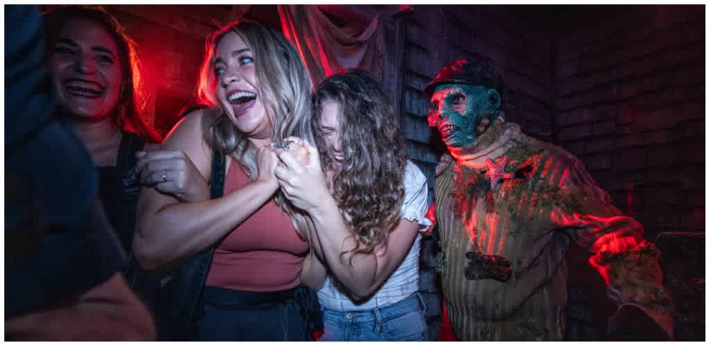 Three terrified women screaming as a Halloween Horror Nights scareactor looms behind them at Universal Studios Florida.