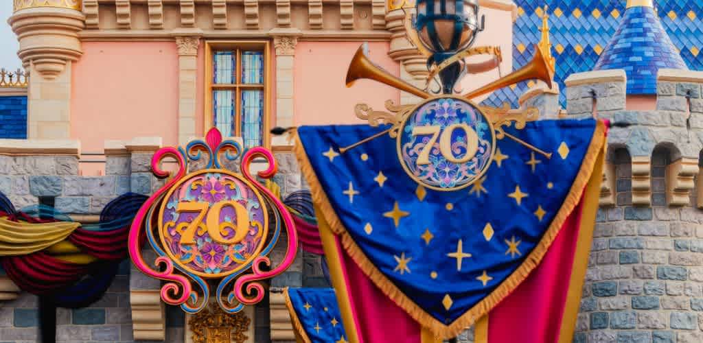 Disneyland Resort 70th Anniversary decorations featuring golden banners and emblems adorning Sleeping Beauty Castle.