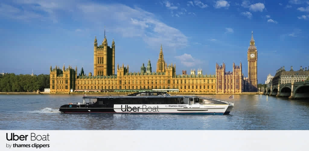 A boat labeled Uber Boat is traveling along the river with the Houses of Parliament and Big Ben in the background in London