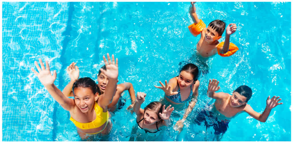 Kids having fun together at a swimming pool during summer.