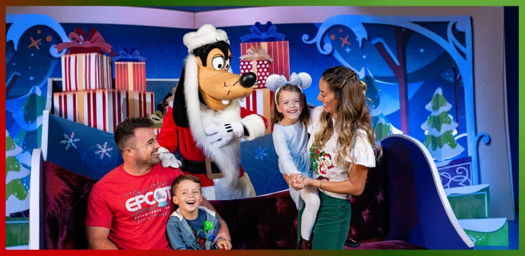 Family enjoying a Christmas event with a person dressed as Goofy and festive winter background