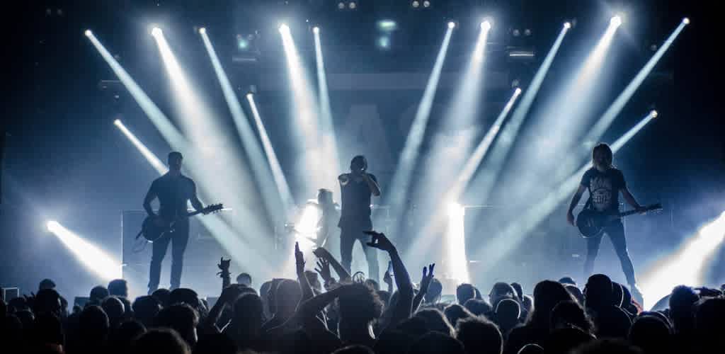A live concert with three musicians performing on stage, bright lights shining down, and an energetic crowd enjoying the performance.