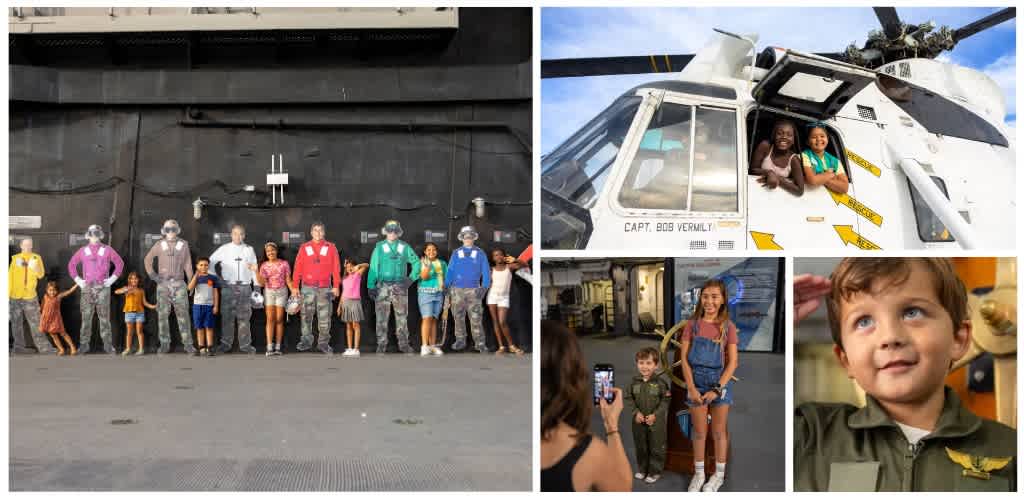 Group of children and adults with military uniforms, standing indoors and taking photos with a helicopter model, children in uniform, and diverse smiles.