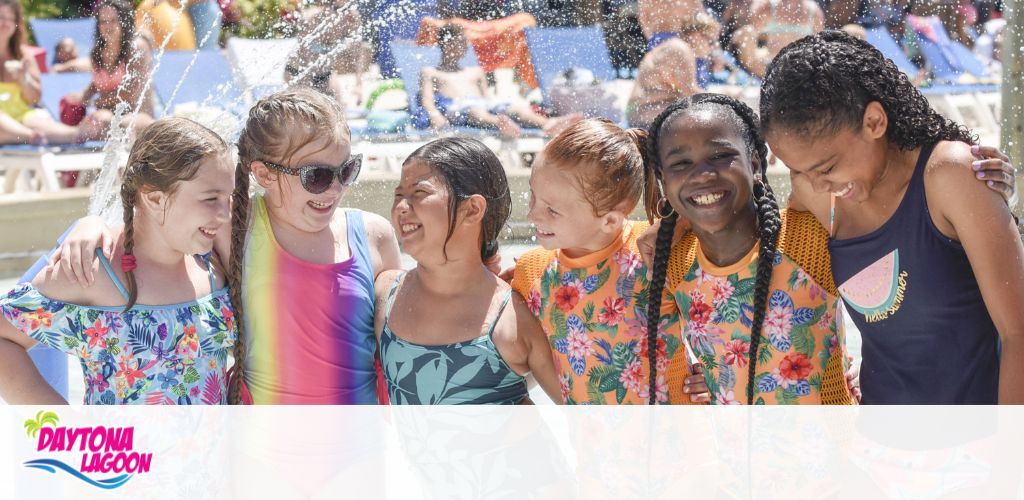 Group of smiling kids at a waterpark with splashing water in the background.