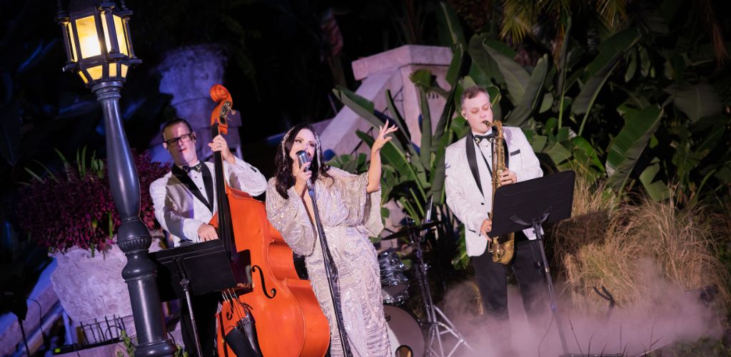  A band performing on stage at night, illuminated by colorful lights, with musicians playing various instruments.