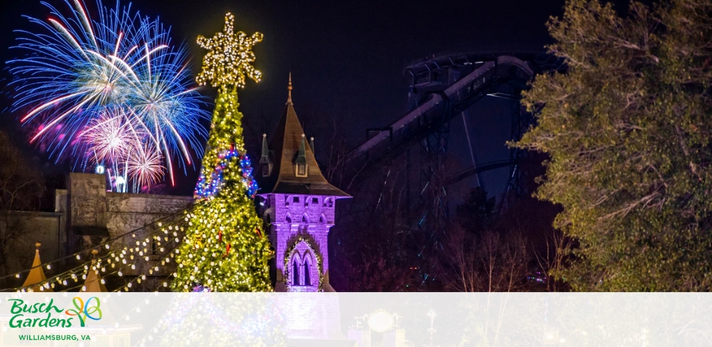 A nighttime scene at Busch Gardens featuring a lit Christmas tree, fireworks, a castle, and a roller coaster.