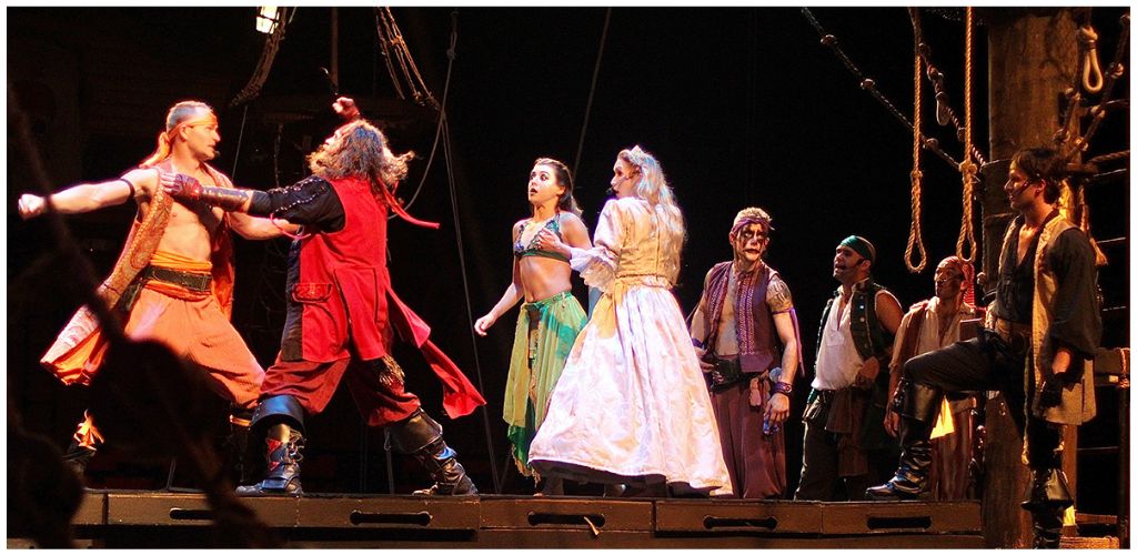 Group of actors performing on stage in pirate costumes in a theatrical production