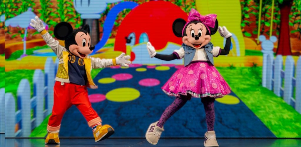 Mickey Mouse and Minnie Mouse characters dancing on a colorful animated outdoor background with trees and a white picket fence.