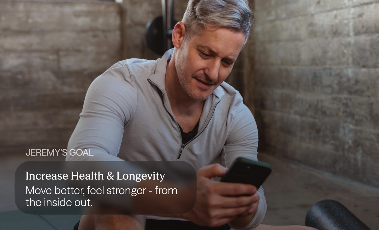 Man sitting in a gym space looking at his phone, with on-screen text about increasing health and longevity.