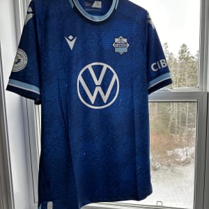 The 2024 Halifax Wanderers' home kit hanging in a window.