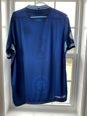 The 2024 Halifax Wanderers' home kit from behind hanging in a window.