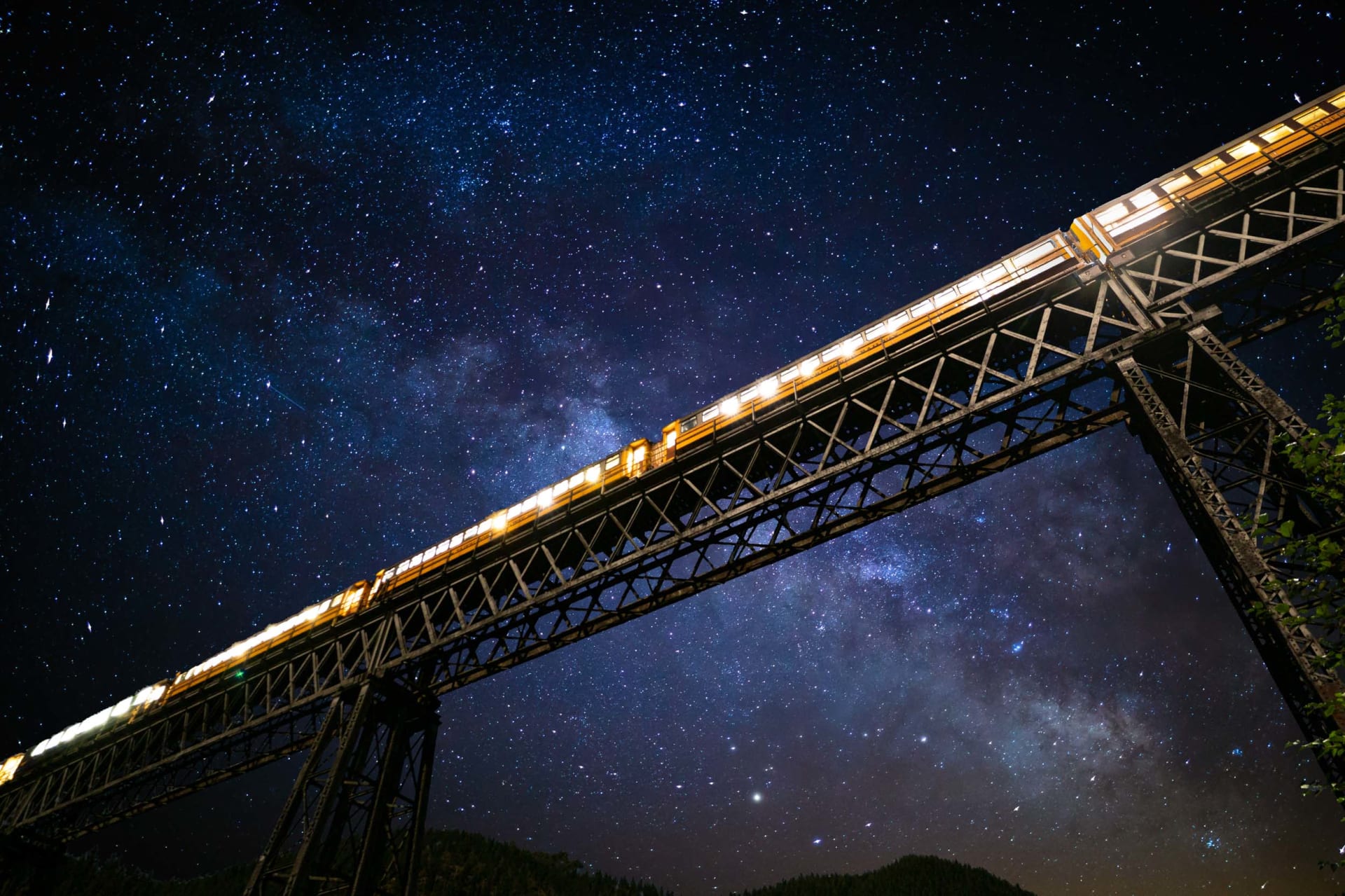 The Taieri Gorge train travels along a winding mountain railway track under a bright sun.