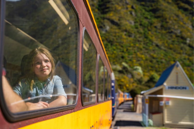 A young girl looks out the window of the Taieri Gorge train next to Hindon train station.