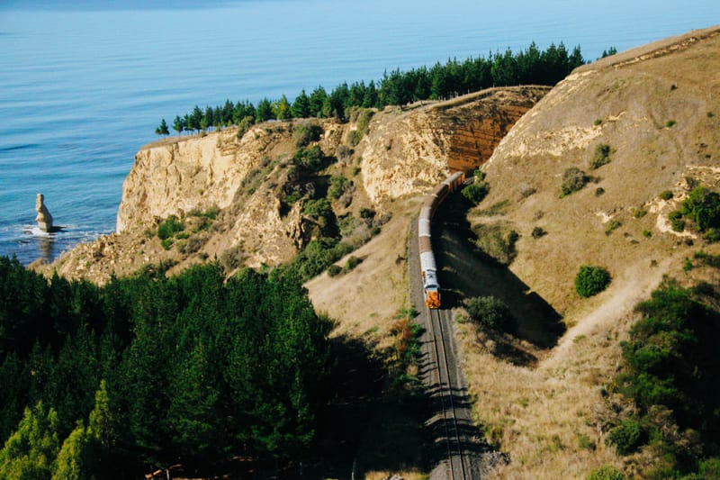 The Seasider train stopped at the Oamaru station platform alongside coastal railway tracks next to the sea.