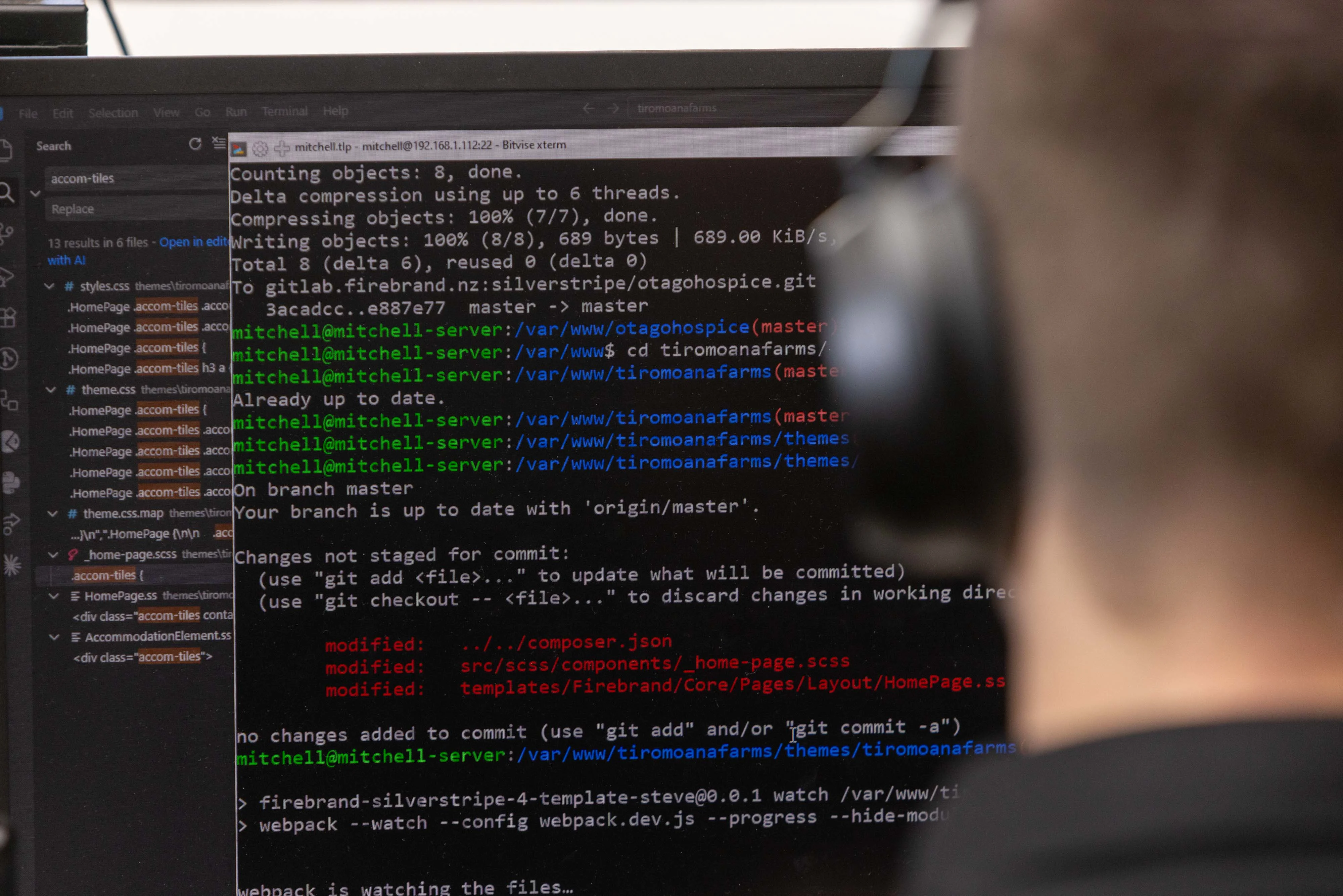 Mitchy writes code at a dual-monitor workstation while wearing headphones.