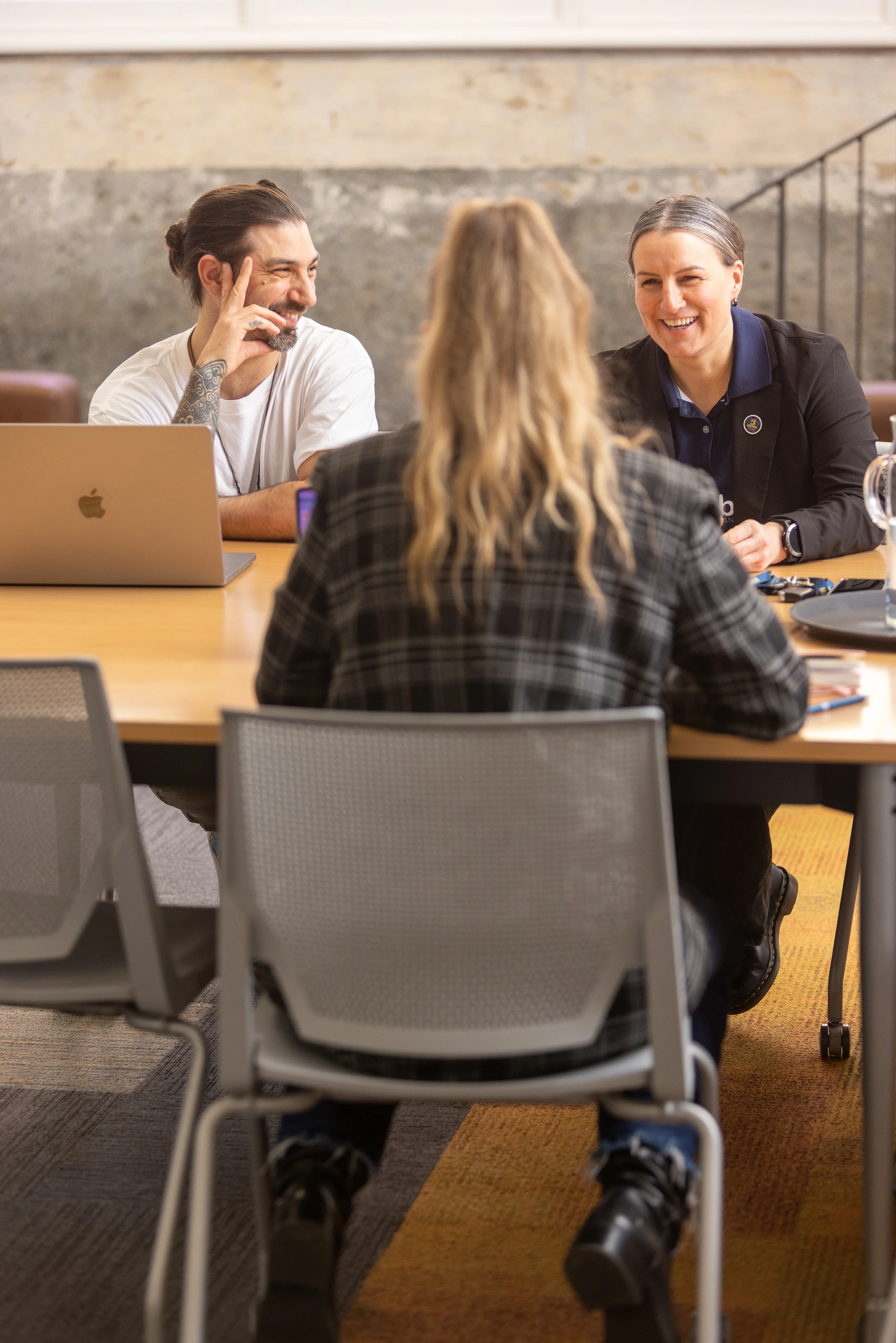 Malcolm chats with two colleagues around a table in the Firebrand office.