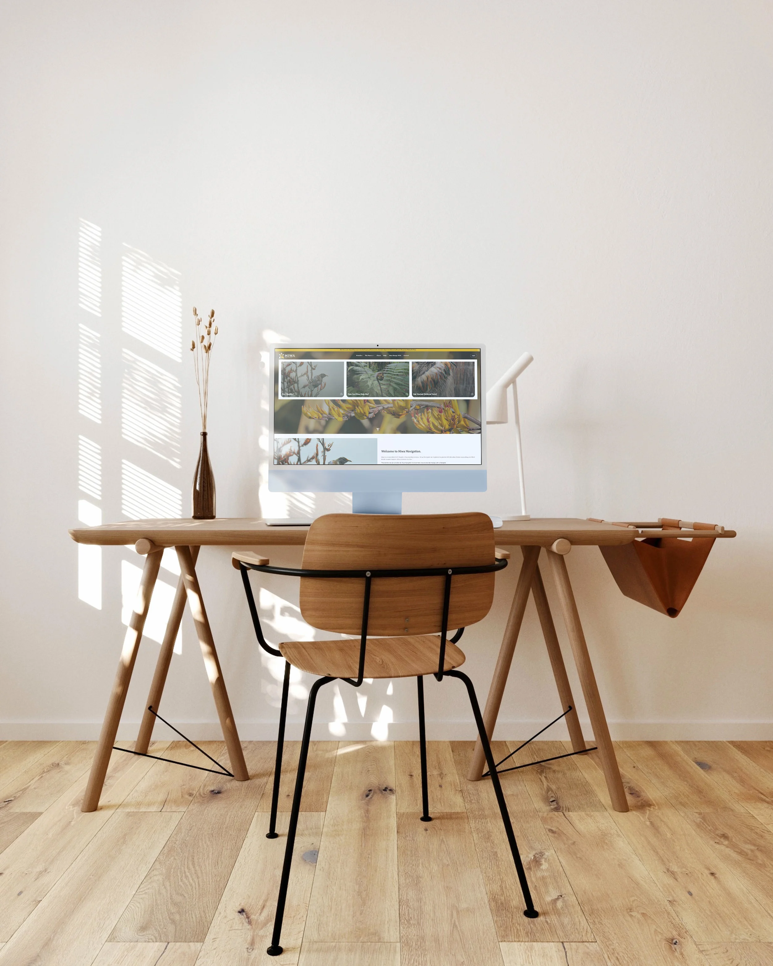 Minimalist home office with the Hiwa Navigation website displayed on a laptop.