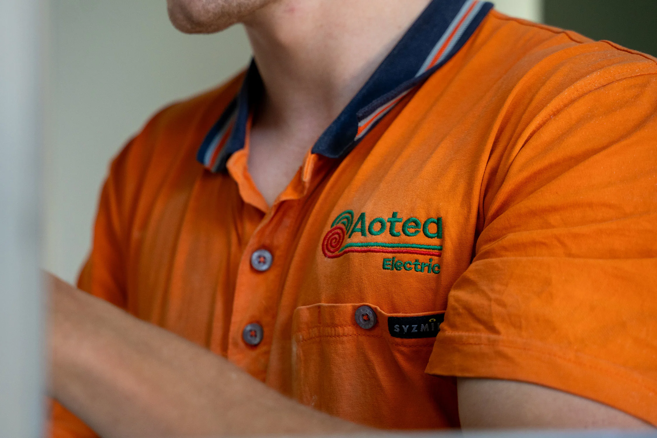 Aotea Electric technician wearing a branded orange uniform.