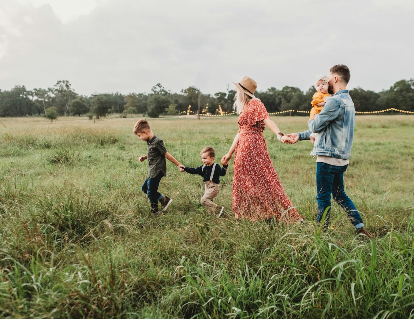 family walking through field holding hands