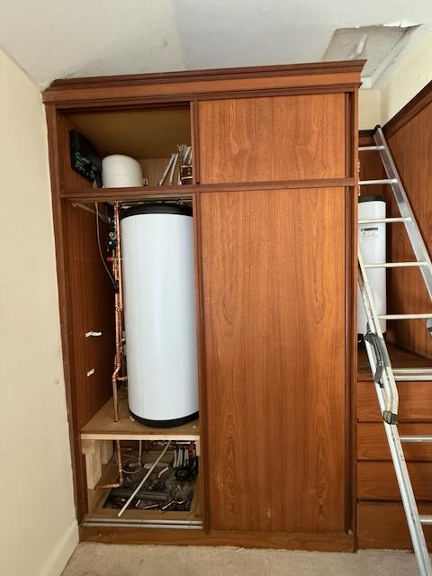 A hot water cylinder and manifold in a wardrobe