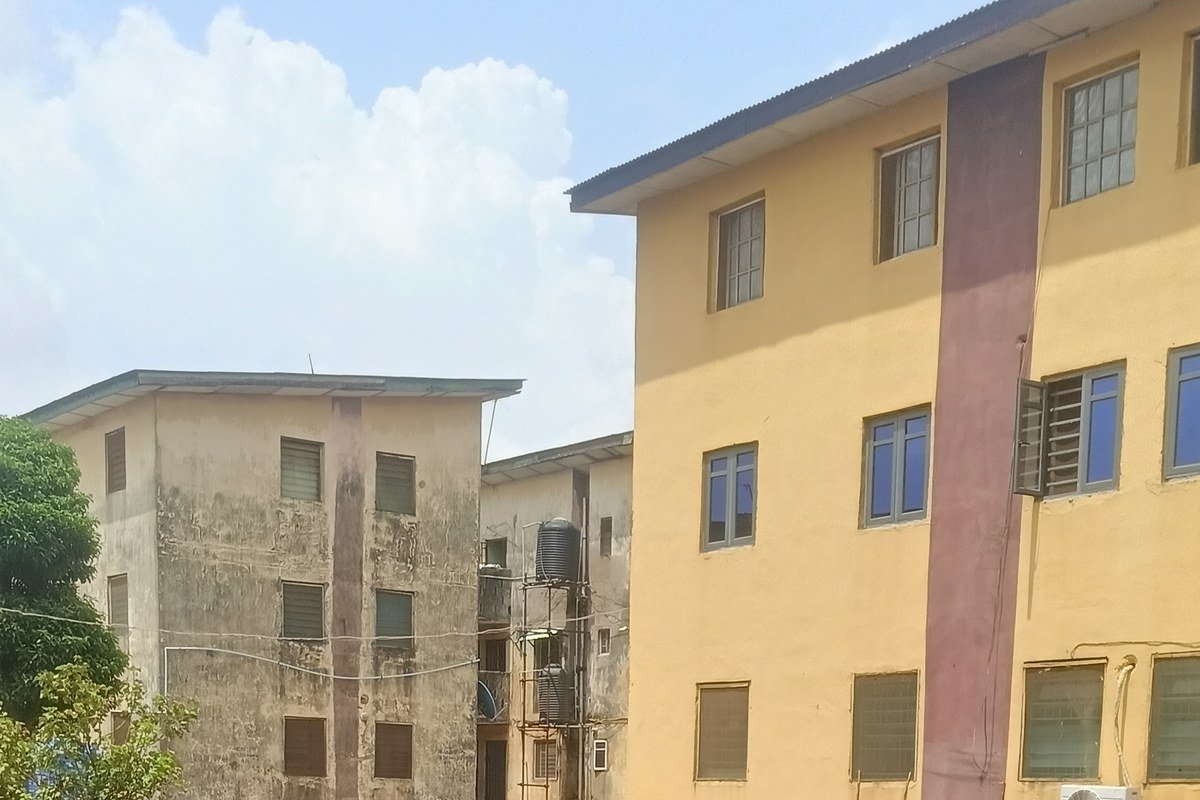 Three-storey residential blocks in a Lagos housing estate, with black water tanks on a steel stand between them