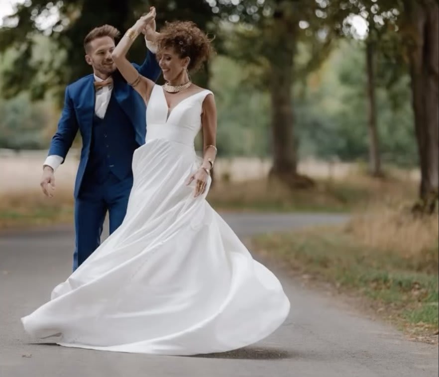 Mariés dansant leur première danse en extérieur, robe envolée