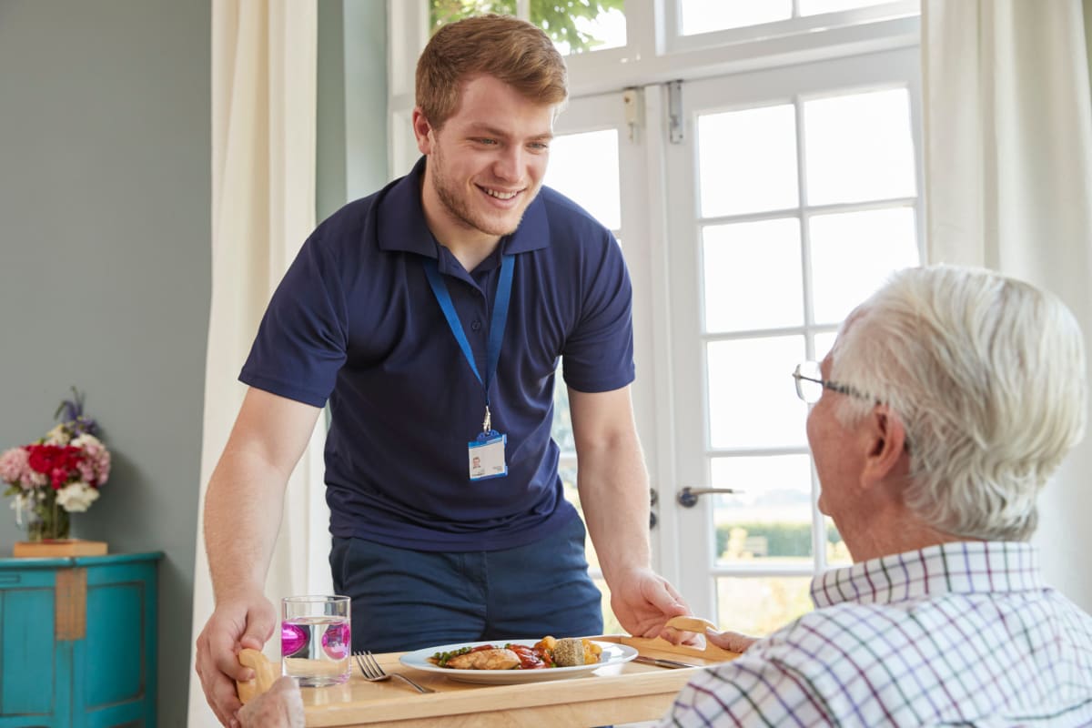 An employee serves a resident a meal at Milestone Retirement Communities in Vancouver, Washington