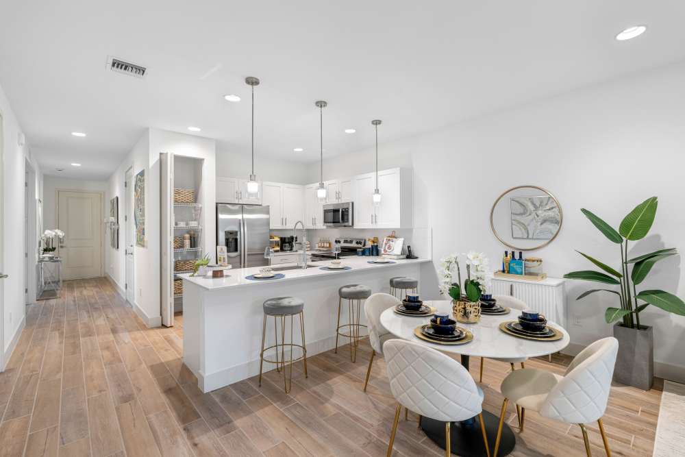 Modern kitchen with stainless steel appliances, granite countertops, and stylish dining area with elegant table setting at Solera at Avalon Trails in Delray Beach, Florida