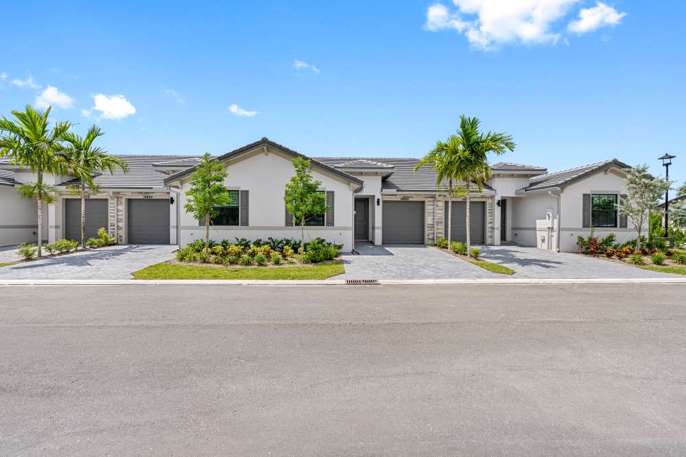 Modern apartment community with landscaped gardens, palm trees, and driveway parking spaces at Solera at Avalon Trails in Delray Beach, Florida